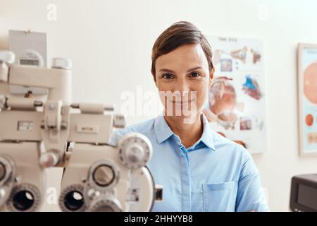 Sto tenendo gli occhi sui tuoi. Ritratto di una donna sicura usando un rifrattore ottico in un ufficio optometristi. Foto Stock
