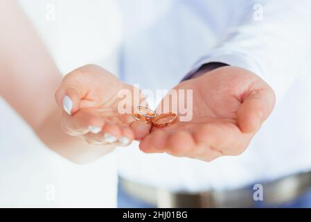 Due anelli di nozze d'oro giacciono sulle palme della sposa e dello sposo. Coppia appena sposata. Messa a fuoco soft Foto Stock