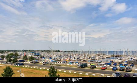 Vista delle barche a vela ormeggiate al molo e parcheggio auto vista dal Centro di vela dell'Università di Kiel in estate con nuvole in cielo blu sfondo. Foto Stock