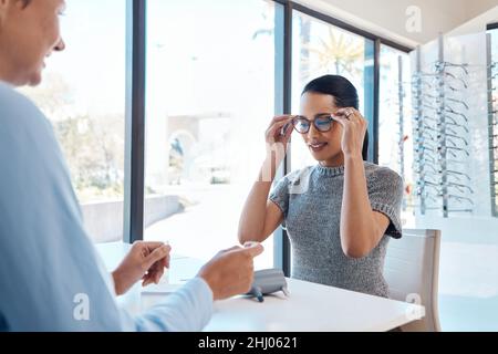 Il momento della verità. Scatto di un optometrist che aiuta una giovane donna a scegliere un nuovo paio di occhiali. Foto Stock