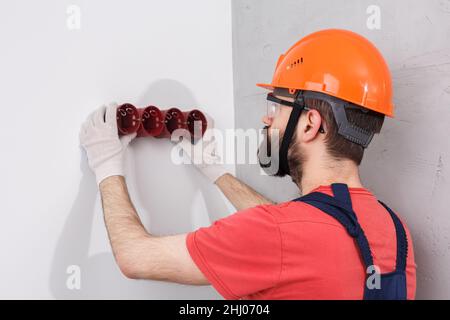 l'elettricista nel casco installa le prese Foto Stock