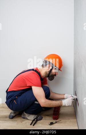 l'elettricista nel casco installa le prese Foto Stock