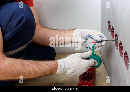 l'elettricista nel casco installa le prese Foto Stock