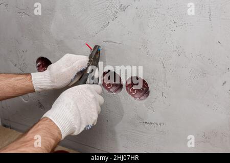 l'elettricista nel casco installa le prese Foto Stock