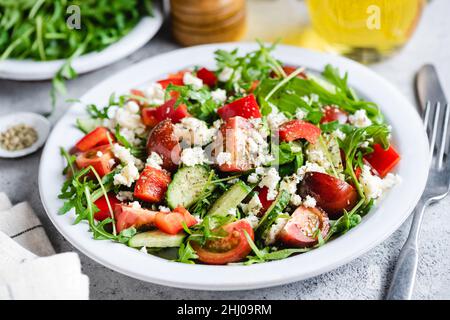 Insalata di verdure con formaggio di capra, foglia di insalata di rucola e pomodori ciliegini su un piatto piatto Foto Stock