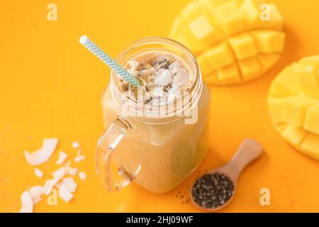 Frullato di cocco Mango con semi di Chia in vaso di vetro su sfondo giallo Foto Stock
