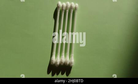 Quattro tamponi di cotone su un tavolo verde. Vista dall'alto, spazio di copia. Foto Stock