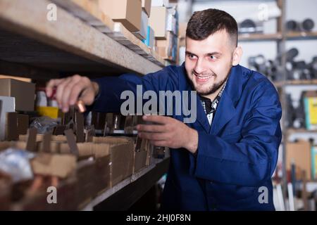 Attraente uomo lavoratore cernita dettagli di ingegneria sanitaria Foto Stock