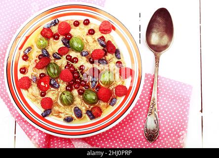 colazione con farinata d'avena con frutti di bosco e miele su sfondo bianco di legno piatto vista dall'alto menu estivo Foto Stock