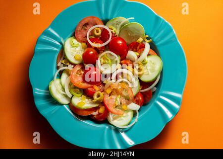 Goiania, Goias, Brasile – 25 gennaio 2021: Un piatto di insalata di verdure su sfondo arancione. Foto Stock