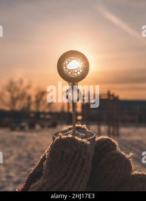 il sole che tramonta brilla attraverso un cerchio in una bolla di sapone bastone in inverno Foto Stock