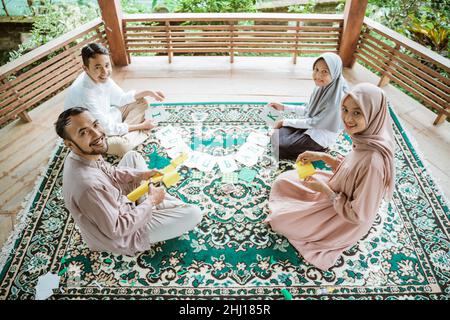 Padre, madre e due figli sorridono facendo carta a catena della bandiera Foto Stock