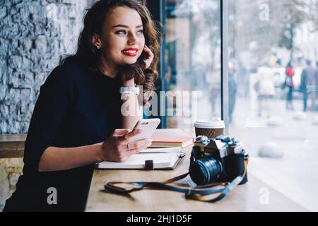 Positivo blogger femminile seduto in bar Foto Stock