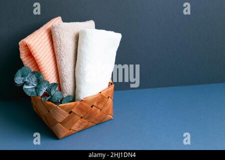 Asciugamano da bagno nel cestino sul tavolo. Sfondo blu scuro parete Foto Stock
