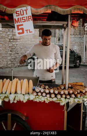 Il venditore di strada cucina e vende mais e castagne sulla strada. Un venditore di strada a Eminonu Foto Stock