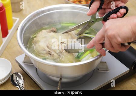hot pot per zuppa di pollo intera coreana, tagliando il pollo intero con le forbici Foto Stock