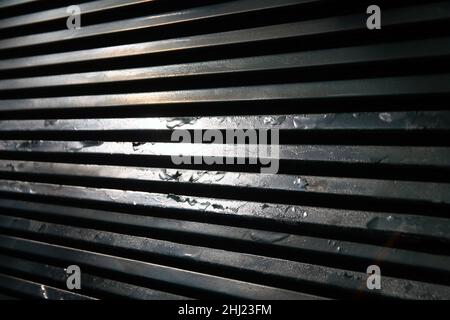 La ruggine di una vecchia griglia metallica con i riflessi del sole in una zona abbandonata Foto Stock