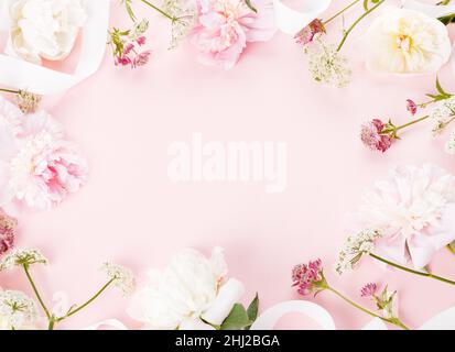 Composizione di fiori. Cornice fatta di romantici fiori rosa di peonia su sfondo rosa. Disposizione piatta, vista dall'alto Foto Stock