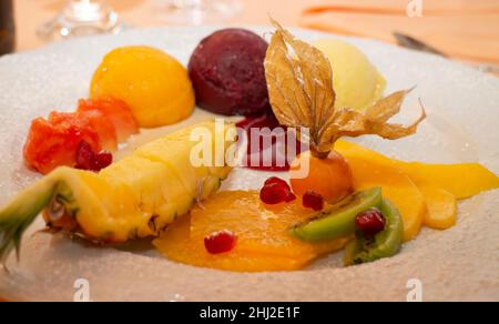 Piatto da dessert con varie fette di frutta e misurini per gelato Foto Stock