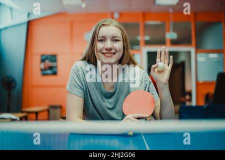 Ritratto di una ragazza sorridente giocatore di ping-pong con una racchetta da ping pong. Mano ondulata Foto Stock