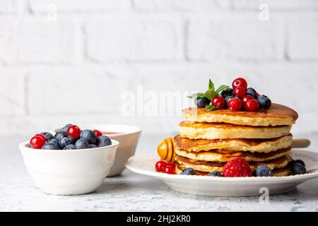 Sana colazione estiva, frittelle classiche americane fatte in casa con frutta fresca e miele, mattina grigio chiaro sfondo pietra copia spazio vista dall'alto Foto Stock