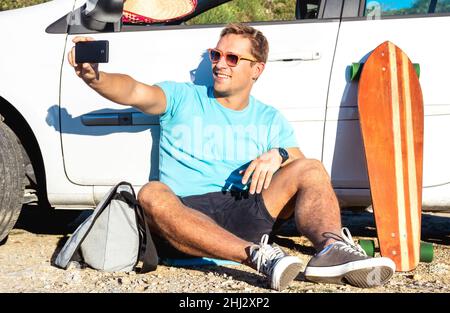 Giovane hipster moda ragazzo prendendo fresco selfie pic dopo la sua auto durante il viaggio - nuove tendenze e viaggio stile di vita concetto mescolato con stile di vita vintage Foto Stock