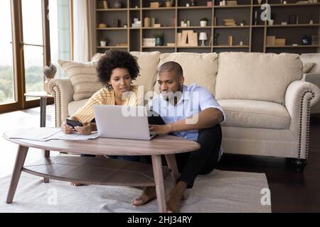 Coppia africana seria che paga le fatture in linea, calcoli le spese nel paese Foto Stock