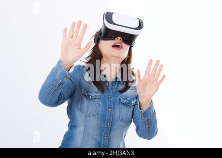 Stupita donna caucasica guardando in un visore VR e gesturando da mani isolate su sfondo bianco. Concetto di realtà virtuale. Copia lo spazio e riponi Foto Stock