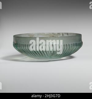 Ciotola in vetro a coste fine 1st secolo a.C.–metà 1st secolo d.C. romana traslucido blu verde.bordo verticale con bordo superiore angolare; Banda piana, verticale intorno alla parte superiore dei lati, poi che si gonfia verso l'esterno prima di curvare in modo deciso a leggermente concava bottom.on interno, tre scanalature concentriche fini intorno al bordo esterno del fondo e piccolo, cerchio più largo al centro; All'esterno, settantasei nervature verticali o leggermente inclinate di lunghezza, larghezza e spessore leggermente variabili, con cime rettificate, disposte intorno a sezione centrale in rilievo di body.intact; bolle di pinprick; vaiolatura, dulling, e iridescence con piccolo Foto Stock