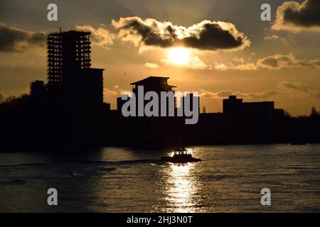 Un piccolo rimorchiatore si dirige verso il Tamigi mentre il sole comincia a tramontare in un'altra giornata invernale a Londra Foto Stock