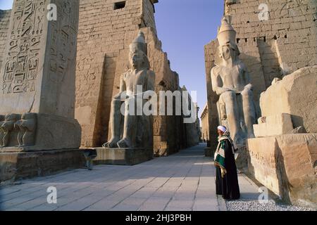 Uomo egiziano in piedi all'ingresso del Tempio di Luxor, Luxor, Egitto Foto Stock
