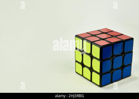 risolto il cubo di rubik in blu, giallo e arancione su sfondo bianco Foto Stock