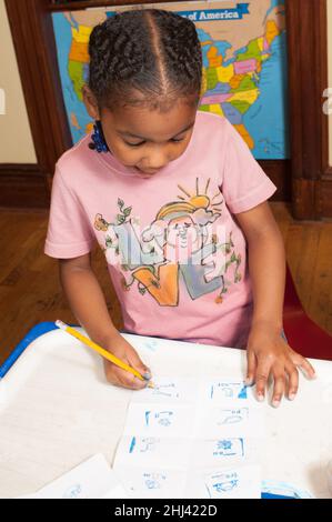 Istruzione Preschool 4-5 anni ragazza usando matita fare attività su carta, tenendolo con treppiede afferrare Foto Stock