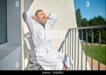 Uomo che si crogiolano nel calore del sole del mattino Foto Stock