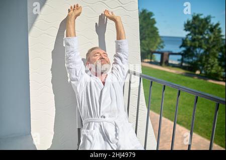 Rilassato uomo dai capelli grigi che si crogiolano al sole Foto Stock