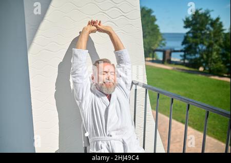 Vacanziere in un accappatoio bianco terry crogiolarsi al sole Foto Stock