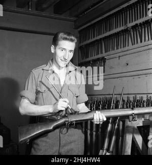 Swansea Town e Wales International Footballer Cliff Jones al servizio del suo National Service con i re truppa Royal Horse Artillery reggimento del British Army.Here sta pulendo il suo fucile per l'ispezione presso le caserme di St John's Wood. 14th ottobre 1957. Foto Stock