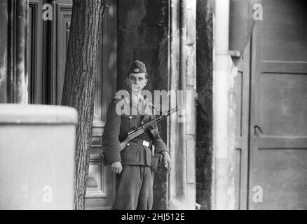 Inizio della costruzione del Muro di Berlino.a mezzanotte il 13th agosto la polizia e le unità dell'esercito tedesco orientale iniziarono a chiudere il confine e, entro domenica mattina, il 13 agosto, il confine con Berlino Ovest fu chiuso. Le truppe e i lavoratori della Germania orientale avevano iniziato a strappare le strade che costeggiano il confine per renderle impraticabili alla maggior parte dei veicoli e per installare intralci di filo spinato e recinzioni lungo i 156 chilometri intorno ai tre settori occidentali, nonché i 43 chilometri che dividono ovest ed est Berlino. Foto mostra: Una guardia di confine della Germania orientale tiene sotto controllo le strade di Foto Stock