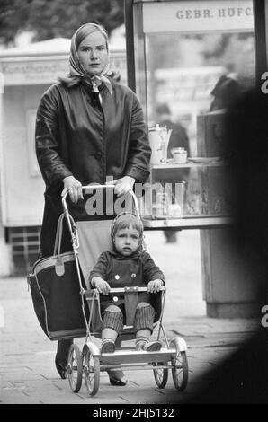 Scene a Berlino Ovest, Germania Ovest che mostrano la vita quotidiana che continua come normale subito dopo l'inizio della costruzione del Muro di Berlino. Giovane madre che spinge il bambino in uno dei quartieri dello shopping della città. 18th agosto 1961. Foto Stock