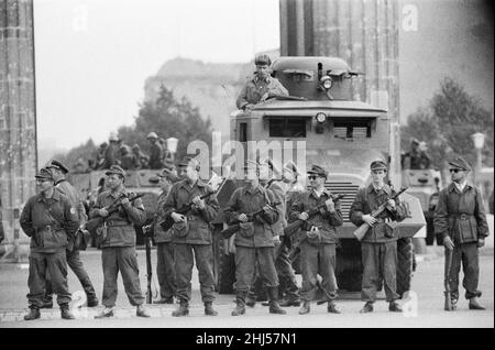 Inizio della costruzione del muro di Berlino. A mezzanotte del 13th agosto la polizia e le unità dell'esercito della Germania orientale cominciarono a chiudere il confine e, entro la domenica mattina del 13 agosto, il confine con Berlino Ovest fu chiuso. La foto scattata tre giorni dopo mostra: I compagni dei gruppi di combattimento della classe operaia, impiegati per proteggere il confine, si trovano pronti presso la porta di Brandeburgo, protetta da un veicolo armato scout della polizia di frontiera. Il sito è stato visitato dal sindaco di Berlino Ovest Willy Brandt e dai generali dell'esercito americano. 16th agosto 1961. Foto Stock