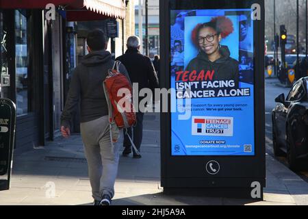 Un uomo cammina oltre l'annuncio digitale del Teenage Cancer Trust. Foto Stock