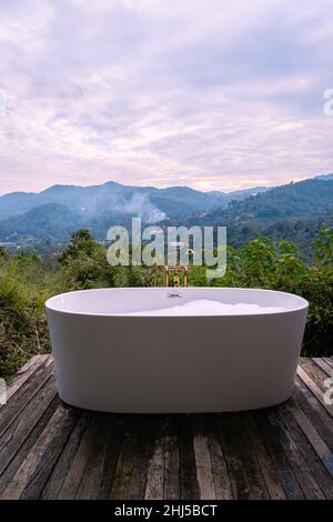 Vasca da bagno durante il tramonto sulle montagne di Chiang mai Thailandia, rilassante in legno camino idromassaggio all'aperto nella natura selvaggia. Bagno rilassante Foto Stock