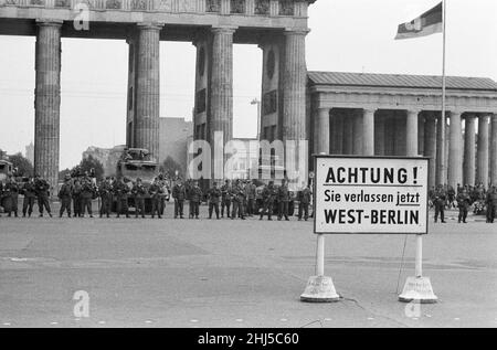 Inizio della costruzione del Muro di Berlino.a mezzanotte il 13th agosto la polizia e le unità dell'esercito tedesco orientale iniziarono a chiudere il confine e, entro domenica mattina, il 13 agosto, il confine con Berlino Ovest fu chiuso. La foto scattata tre giorni dopo mostra: I compagni dei gruppi di combattimento della classe operaia, impiegati per proteggere il confine, si trovano pronti presso la porta di Brandeburgo, protetta da un veicolo armato scout della polizia di frontiera. Il sito è stato visitato dal sindaco di Berlino Ovest Willy Brandt e dai generali dell'esercito americano. 16th agosto 1961. Foto Stock