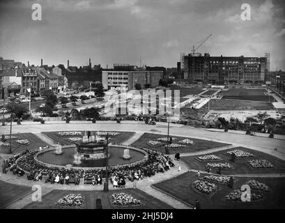 Le fontane che si schizzano in modo allegro tra aiuole di fiori si abbelliscono di colore, gli acquirenti che riposano un po' al sole di agosto aiutano a fare questa foto di un nuovo look Queen's Gardens, Hull. Sullo sfondo si trova il nuovo college di tecnologia che nudofing Hull City Police quartier generale sulla sinistra. Questa vista è stata presa dal tetto degli uffici del molo di Hull. 25th agosto 1960 Foto Stock