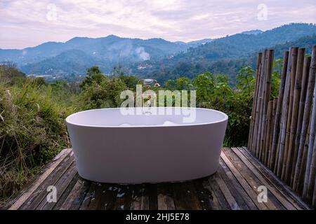 Vasca da bagno durante il tramonto sulle montagne di Chiang mai Thailandia, rilassante in legno camino idromassaggio all'aperto nella natura selvaggia. Bagno rilassante Foto Stock