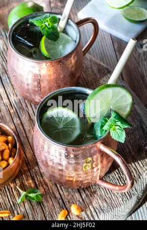 Mosca Mule cocktail in brocche di rame gelate per rimanere freddo, guarnito con lime. Foto Stock