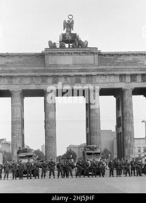 Inizio della costruzione del muro di Berlino. A mezzanotte del 13th agosto la polizia e le unità dell'esercito della Germania orientale cominciarono a chiudere il confine e, entro la domenica mattina del 13 agosto, il confine con Berlino Ovest fu chiuso. La foto scattata tre giorni dopo mostra: I compagni dei gruppi di combattimento della classe operaia, impiegati per proteggere il confine, si trovano pronti presso la porta di Brandeburgo, protetta da un veicolo armato scout della polizia di frontiera. Il sito è stato visitato dal sindaco di Berlino Ovest Willy Brandt e dai generali dell'esercito americano. 16th agosto 1961. Foto Stock