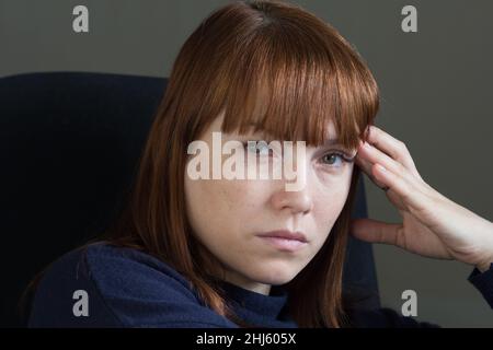 Ritratto di donna di mezza età con un aspetto triste e infelice tenendo la mano vicino alla testa e guardando la fotocamera Foto Stock