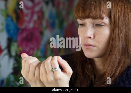 Ritratto di donna di mezza età guardando le sue unghie dispiaciuto Foto Stock