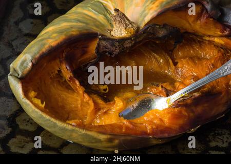 Metà della zucca cotta al forno con cucchiaio sulla teglia da forno Foto Stock